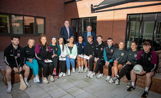 Sitting at the front are the 16 recipients of the GAA student bursaries and standing behind them are St Mary's Principal, Professor Peter Finn and Ulster GAA President, Mr Ciaran McLaughlin.  The first student seated on the right is holding a hurley stick and the last student on the right is holding a gaelic football.